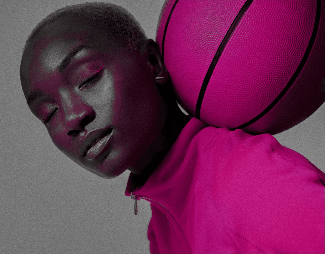 Jogadora de cabeça inclinada apoiando uma bola de basquete no ombro, em tratamento duotone rosa.