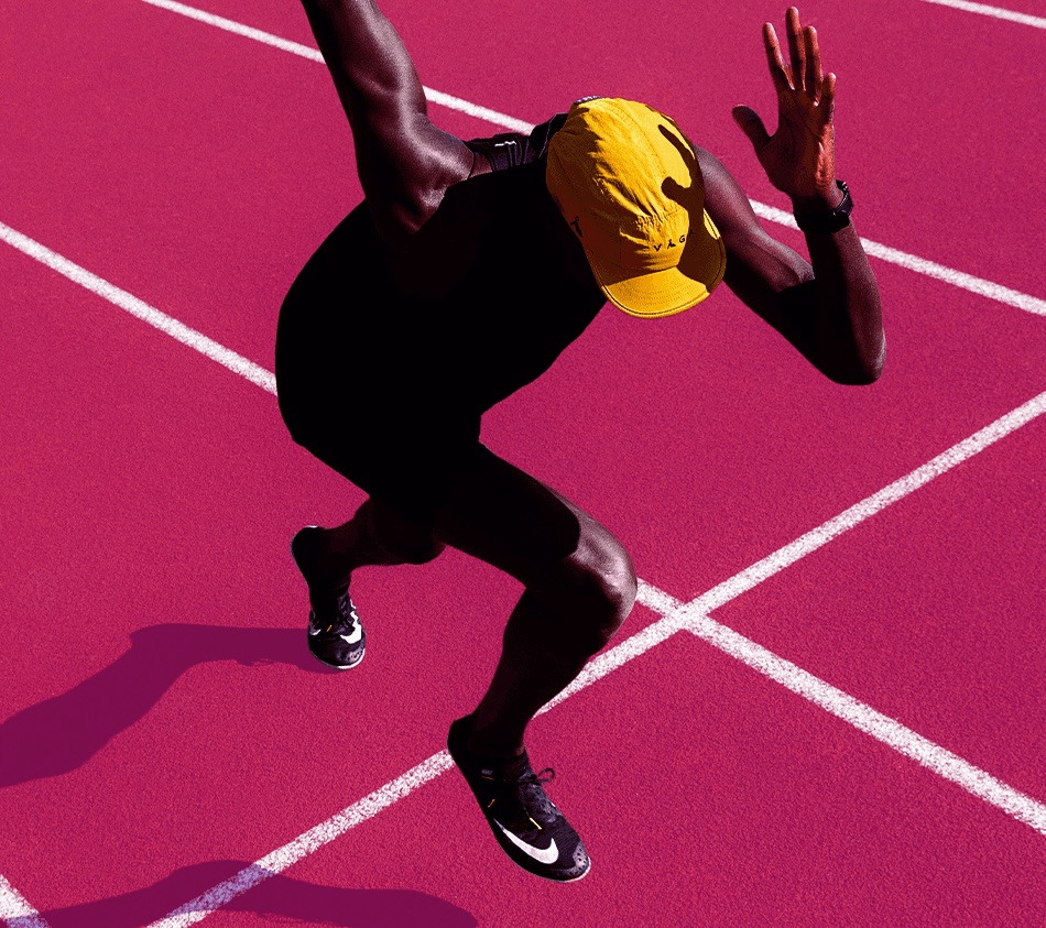 Atleta em posição de largada numa pista de atletismo, em tratamento duotone rosa.