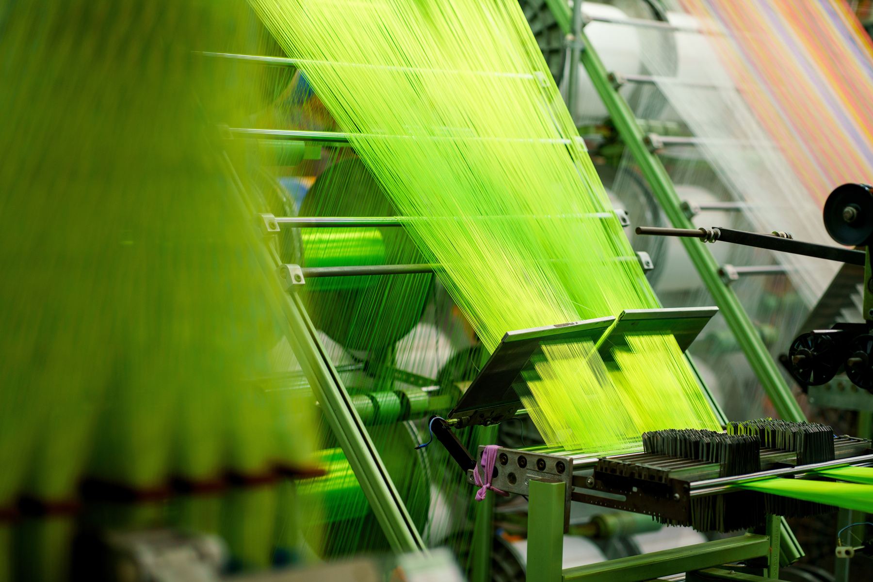 Tear industrial da Globalfit em operação, com dezenas de fios verdes fluorescentes sob tensão.