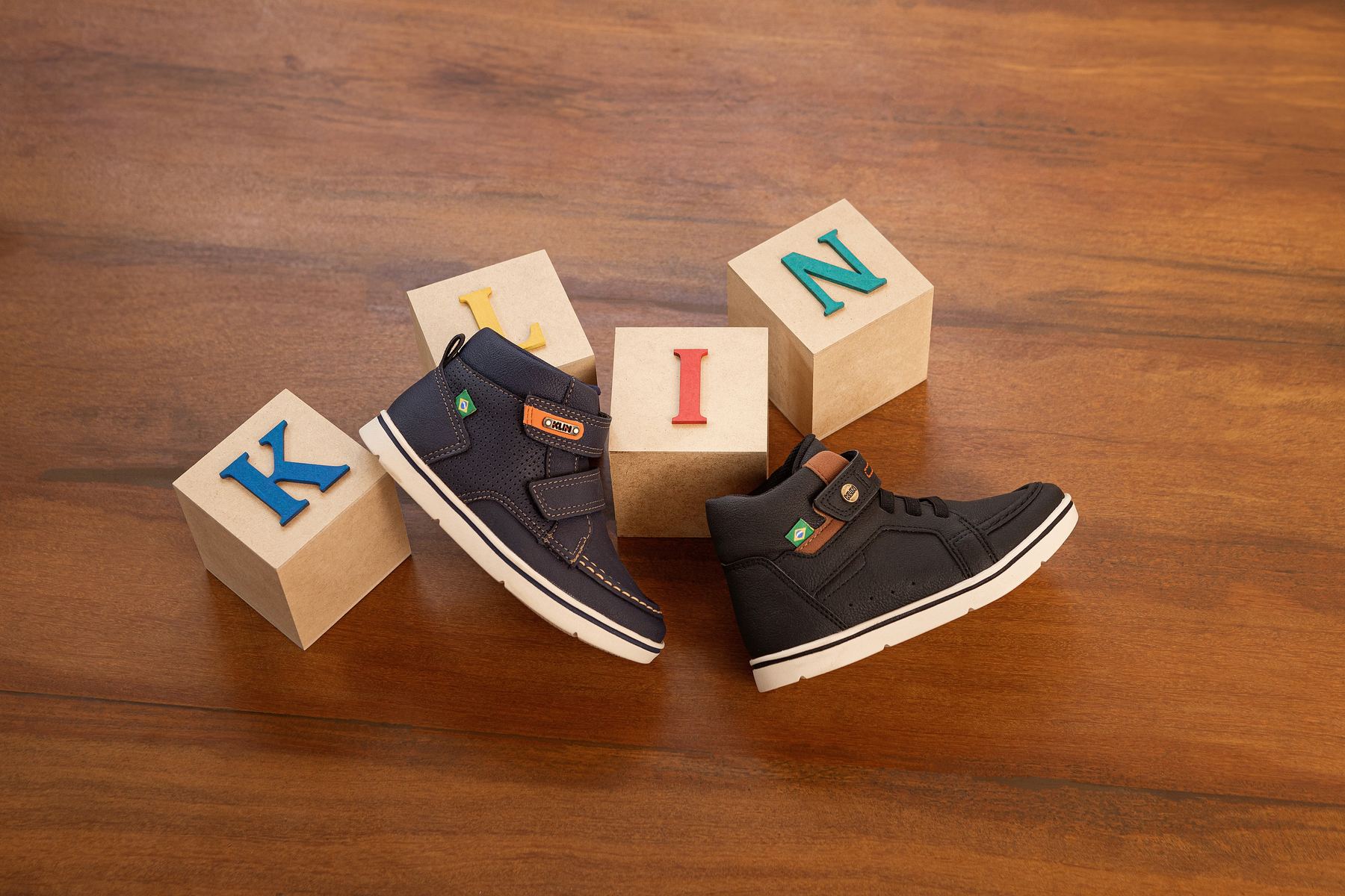 Tênis infantil Klin ao lado de cubos de madeira com as letras K, I e N.