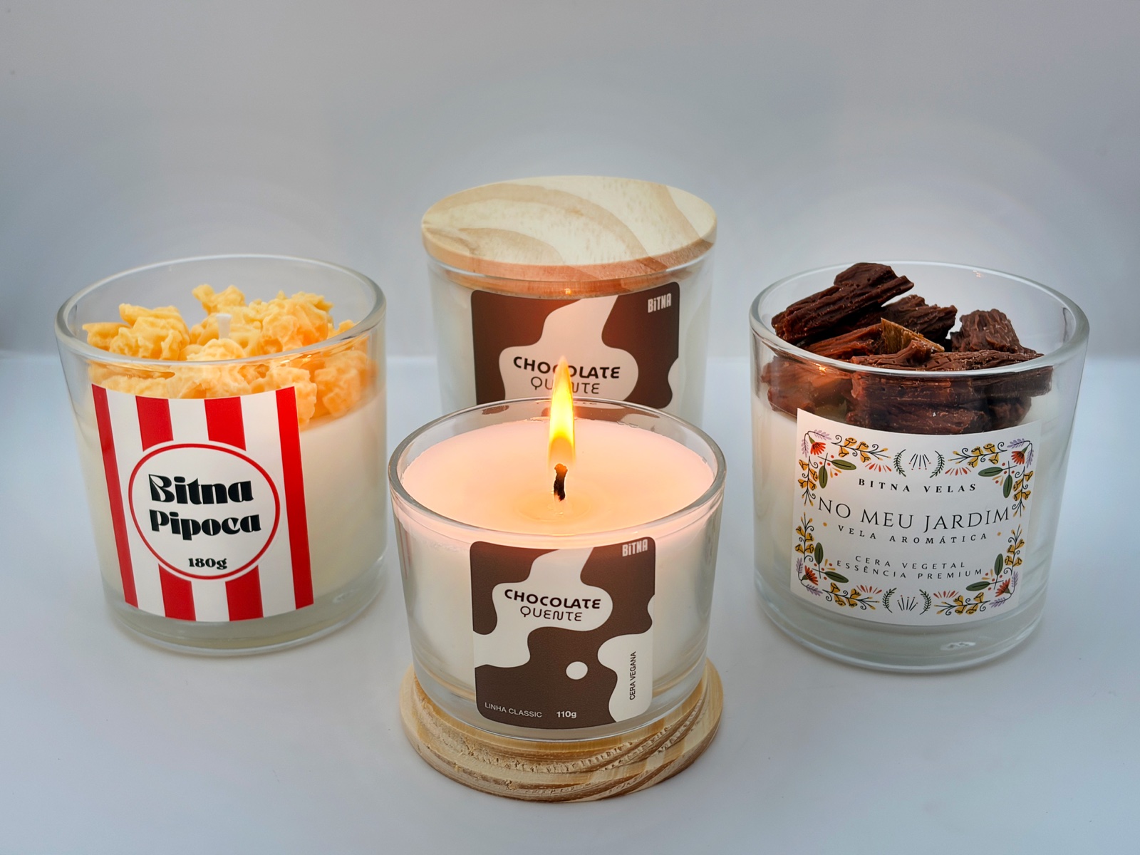 Quatro velas aromáticas da Bitna em estúdio, com a vela de chocolate quente acesa ao centro.